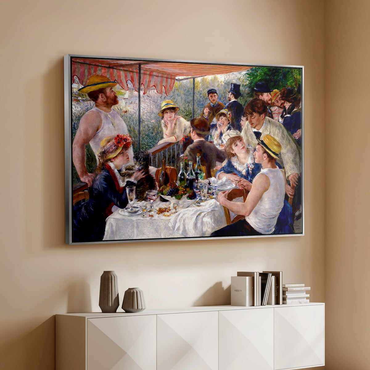 Silver floater framed canvas of Luncheon of the Boating Party (Le Déjeuner des canotiers), 1880-1881 by Pierre-Auguste Renoir, featuring a lively gathering of men and women eating and socializing at outdoor table above a console cabinet in a minimalist entryway.