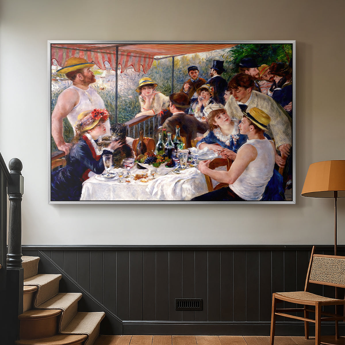 Silver floater framed canvas featuring a social dining scene with figures seated around table on riverside terrace, displayed in a hallway near a staircase.
