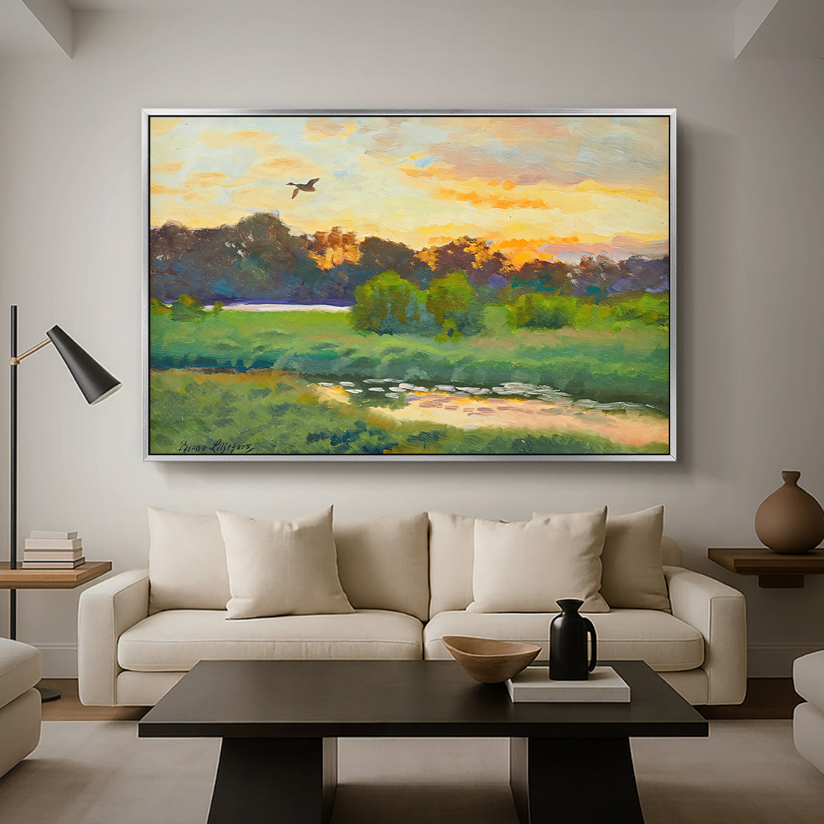 Flying Duck at Sunset, 1924 by Bruno Liljefors as a silver floater framed canvas featuring a wild duck flying over a sunset marsh with trees, displayed above a sofa in a modern living room.
