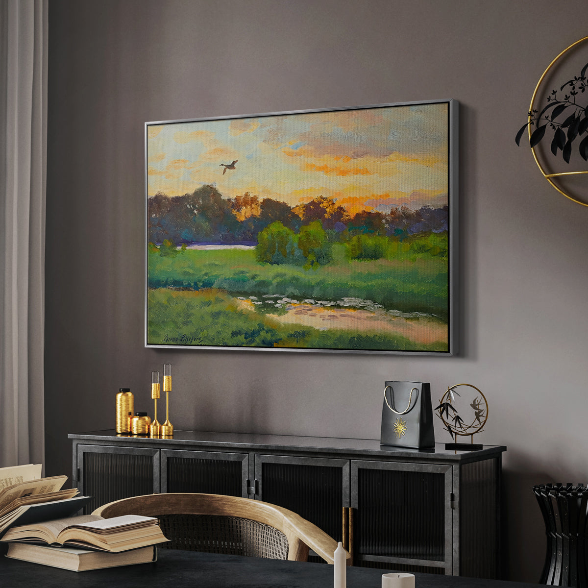 Flying Duck at Sunset, 1924 by Bruno Liljefors in a silver floater framed canvas featuring a wild duck gliding through a golden sunset sky, displayed above a desk in a dark home office interior.