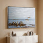 Silver floater framed canvas of Greylag Geese (Grågäss), 1922 by Bruno Liljefors, featuring birds standing and resting along shoreline with soft grass and water above a console cabinet in a minimalist entryway.