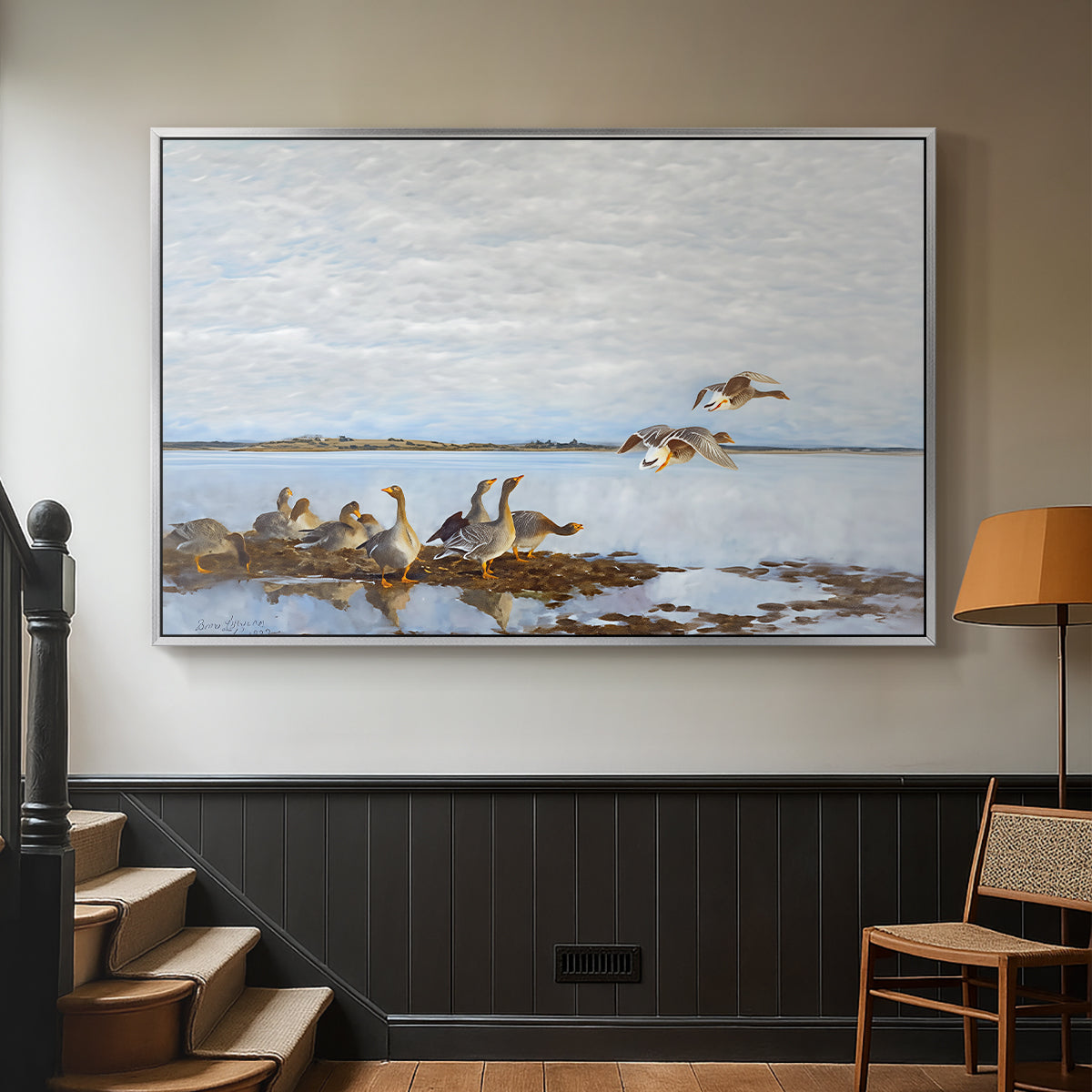 Silver floater framed canvas featuring a flock of geese positioned along marshy terrain, displayed in a hallway near a staircase.