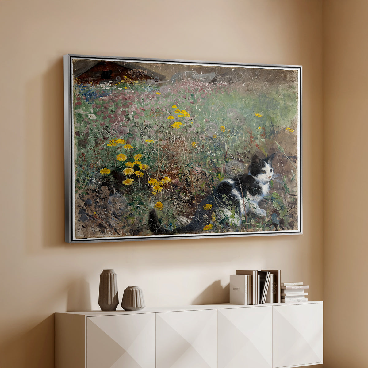 Silver floater framed canvas of Cat on a Flowery Meadow, 1887 by Bruno Liljefors, featuring a small cat resting among colorful flowers in grassy field above a console cabinet in a minimalist entryway.