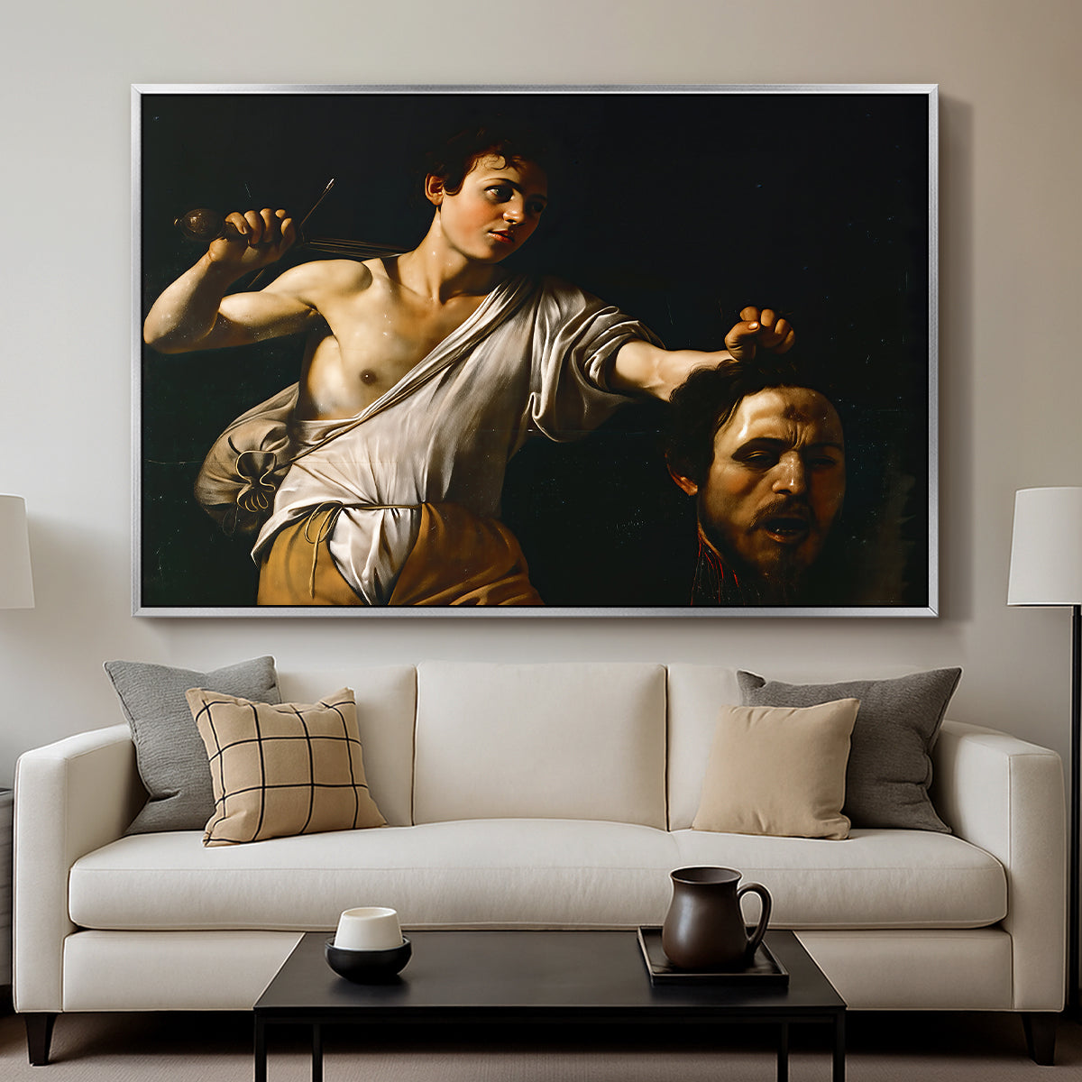 David with the Head of Goliath (Vienna Version), c. 1607 by Caravaggio displayed in a silver floater framed canvas above a sofa in a clean living room.