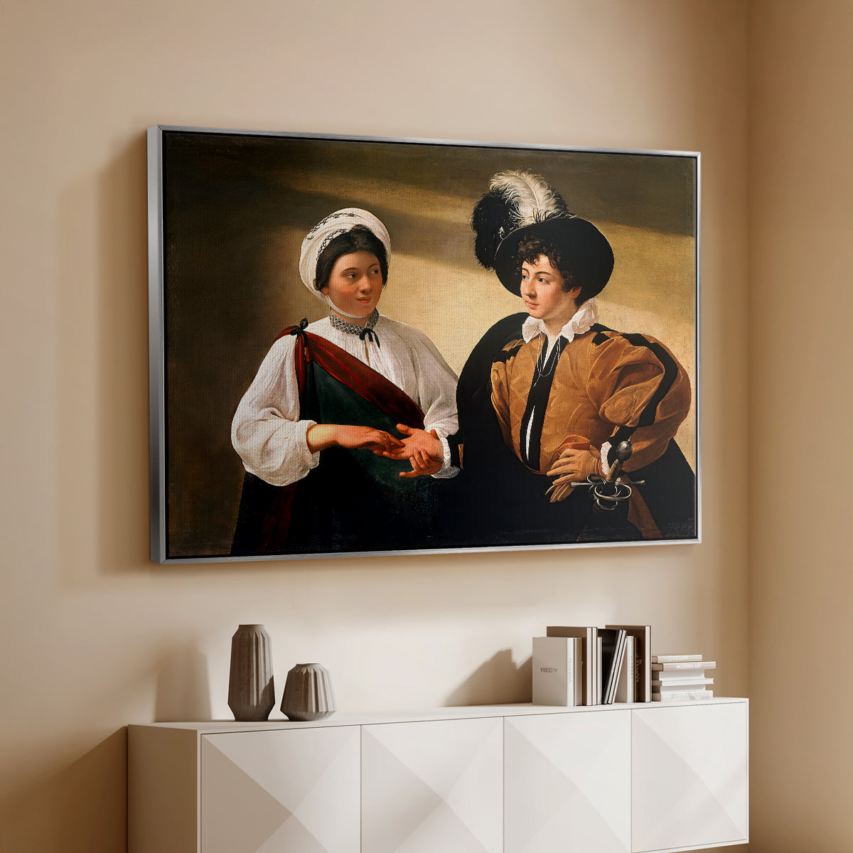Silver floater framed canvas of The Fortune Teller (Louvre Version), c. 1595 by Caravaggio, featuring a fortune teller examining hand of man as she slyly removes his ring above a console cabinet in a minimalist entryway.