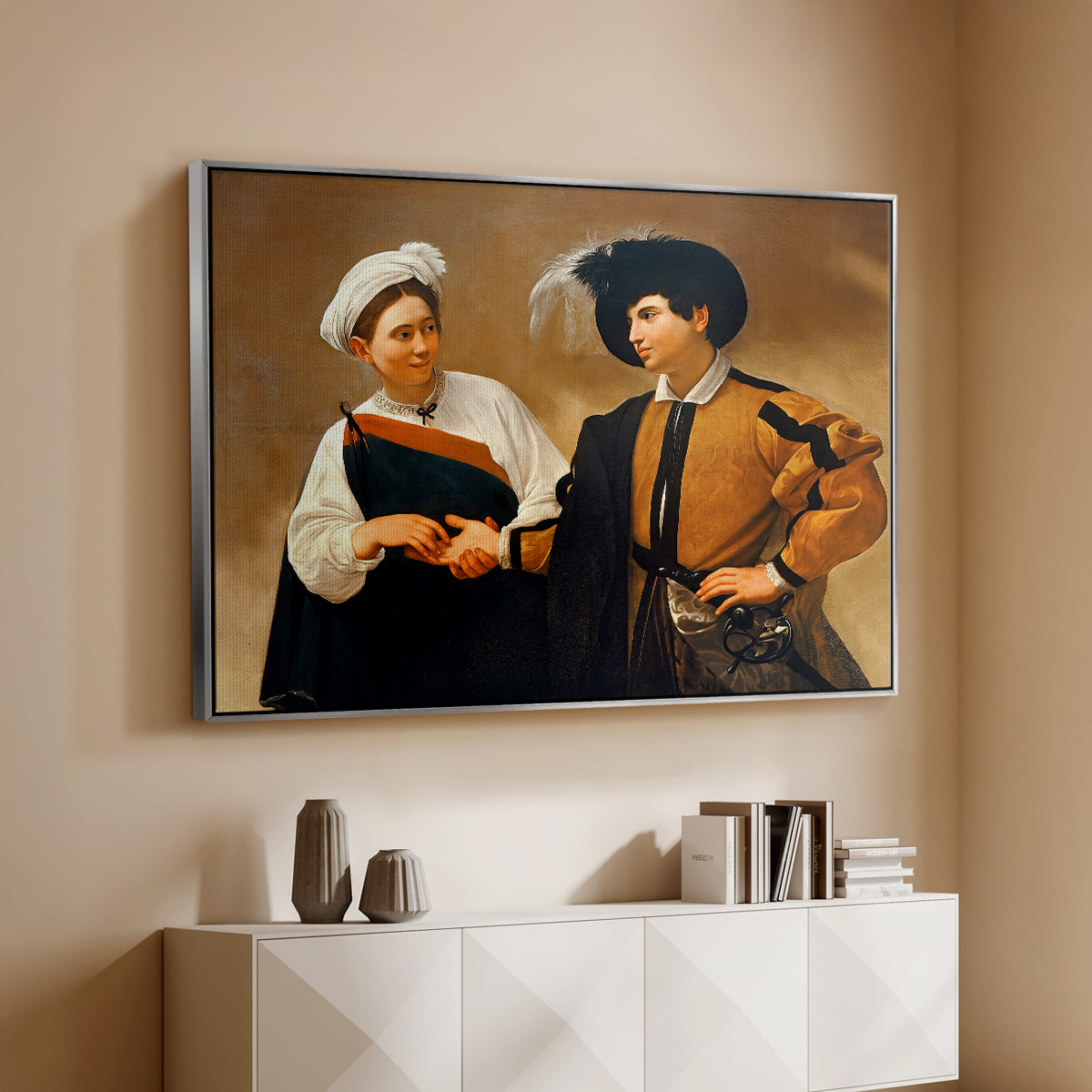 Silver floater framed canvas of The Fortune Teller (Capitoline Version), c. 1599 by Caravaggio, featuring a fortune teller tricking young man during palm reading above a console cabinet in a minimalist entryway.
