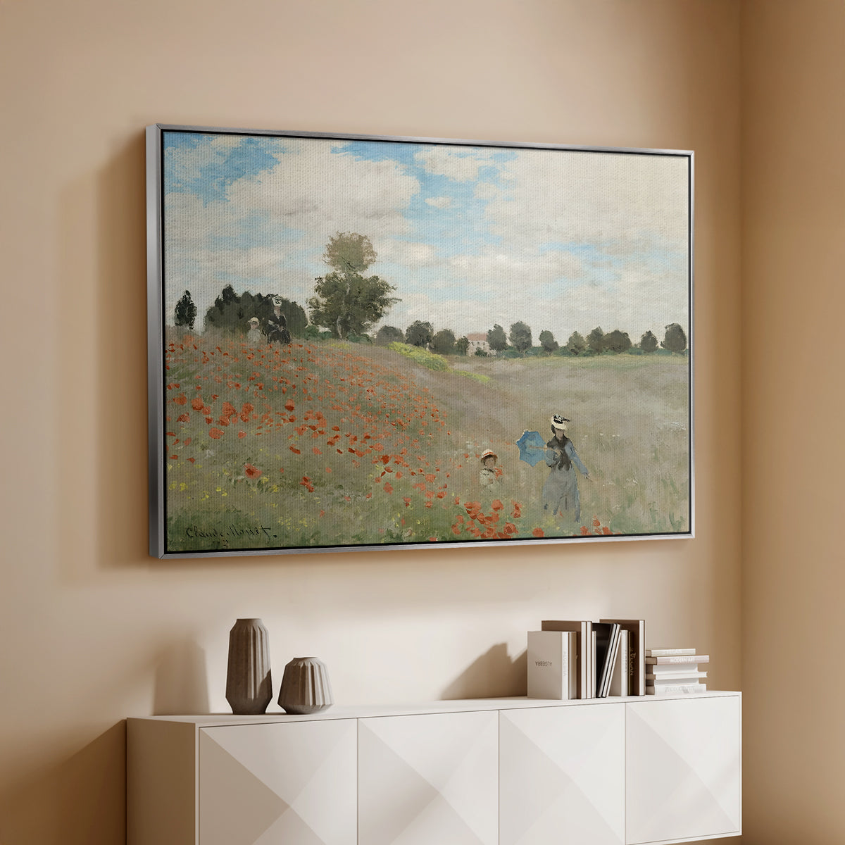Silver floater framed canvas of The Poppy Field near Argenteuil, 1873 by Claude Monet, featuring an impressionist countryside scene with flowers and strolling figures above a console cabinet in a minimalist entryway.