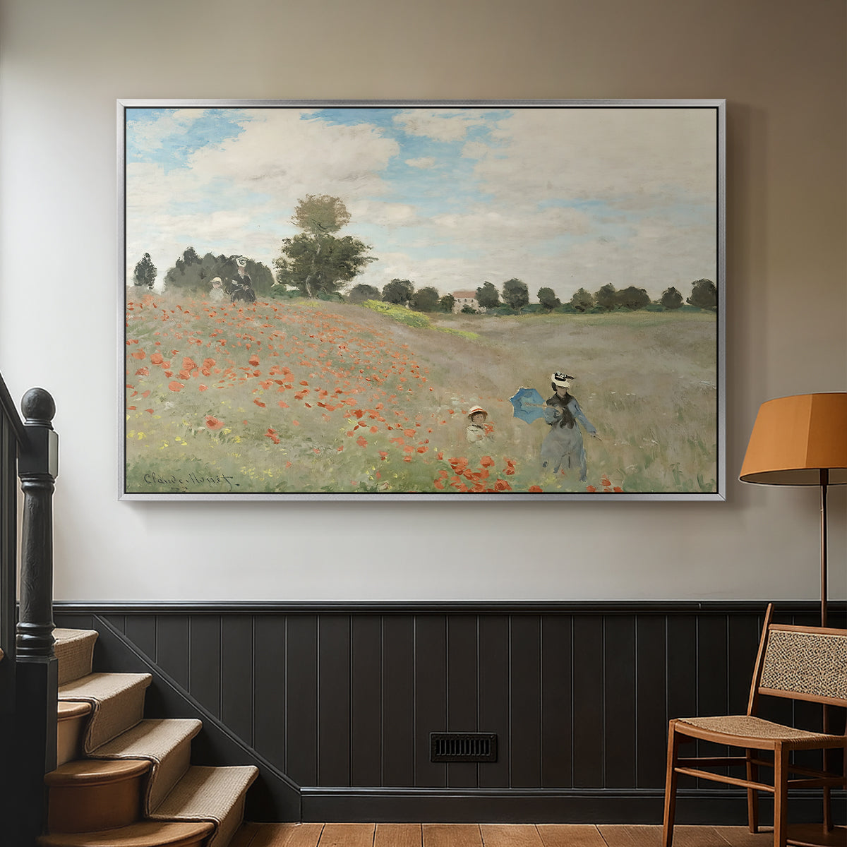 Silver floater framed canvas featuring a rural landscape with scattered figures among blooming flowers, displayed in a hallway near a staircase.