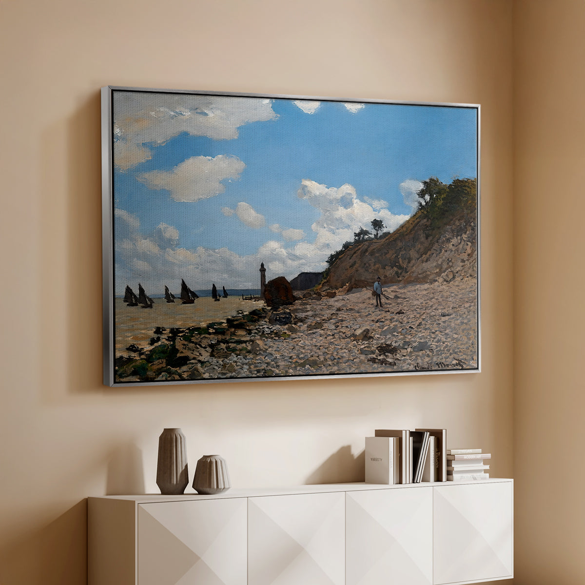 Silver floater framed canvas of The Beach at Honfleur, 1864 by Claude Monet, featuring an impressionist seaside with people and sailboats under bright sky above a console cabinet in a minimalist entryway.