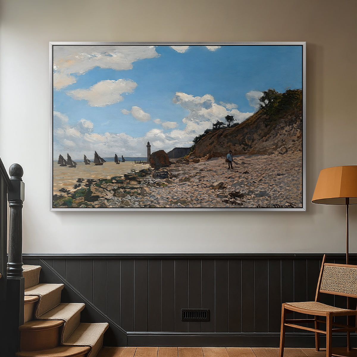 Silver floater framed canvas featuring a coastal landscape with boats and people along shore, displayed in a hallway near a staircase.
