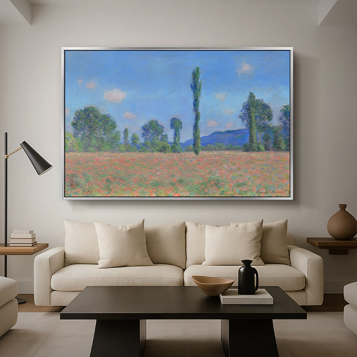 Poppy Field (Giverny), 1890-1891 by Claude Monet as a silver floater framed canvas featuring an expansive field of red poppies with tall trees under blue sky, displayed above a sofa in a modern living room.