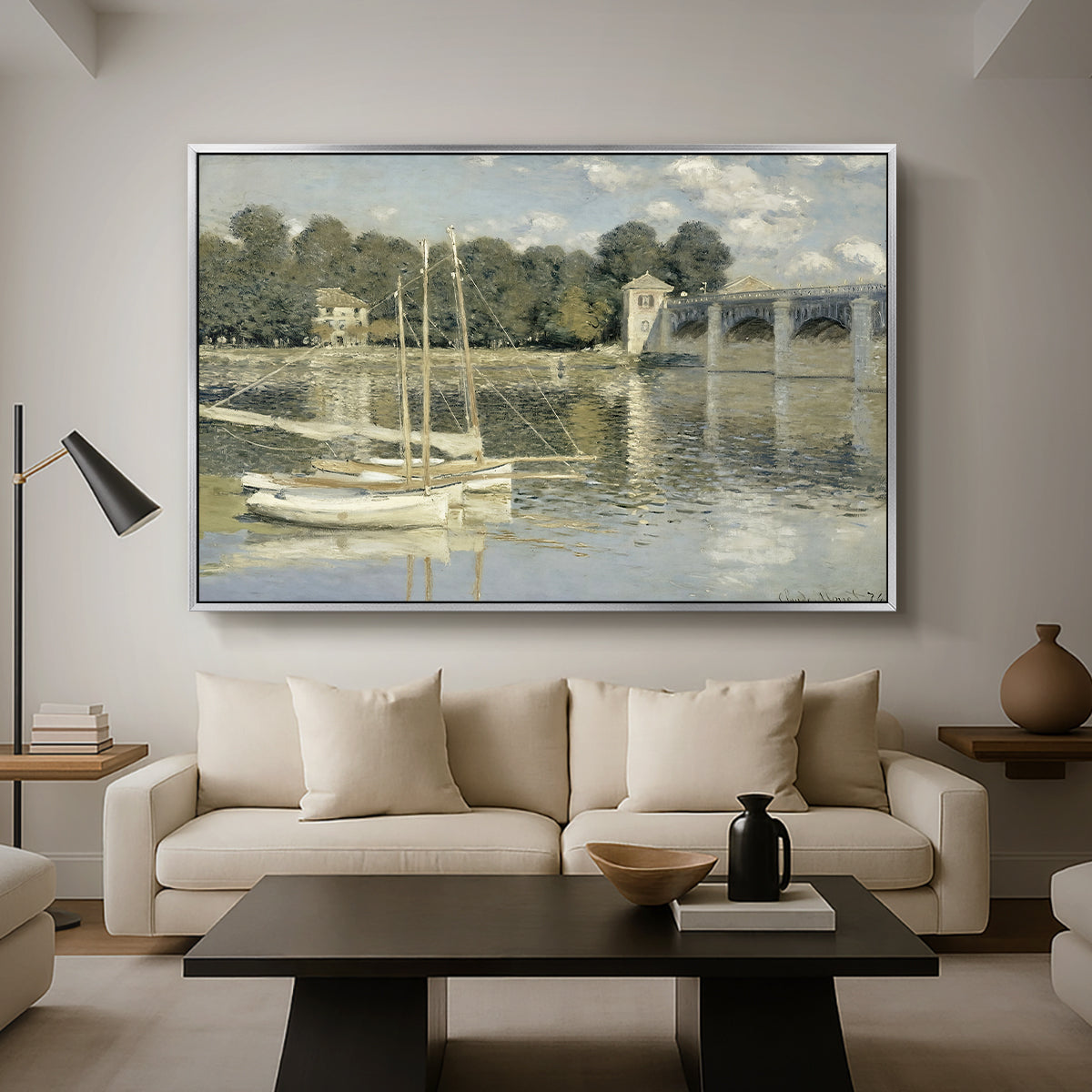 The Bridge at Argenteuil, 1874 by Claude Monet as a silver floater framed canvas featuring a bridge spanning river with sailboats and reflections in water, displayed above a sofa in a modern living room.