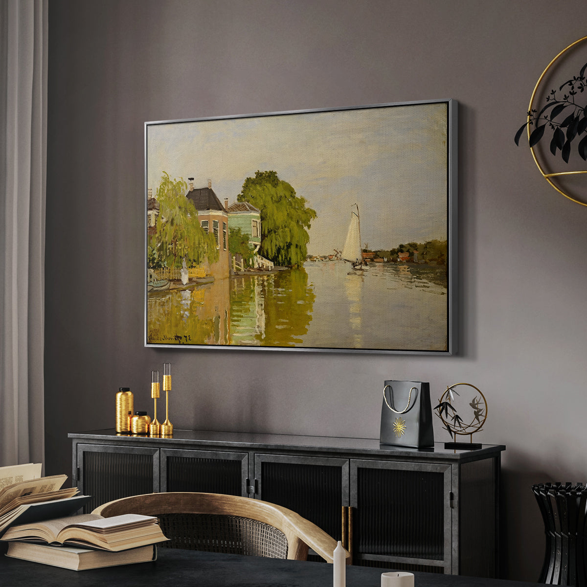 Houses on the Achterzaan, 1871 by Claude Monet in a silver floater framed canvas featuring an impressionist landscape with buildings along quiet canal, displayed above a desk in a dark home office interior.