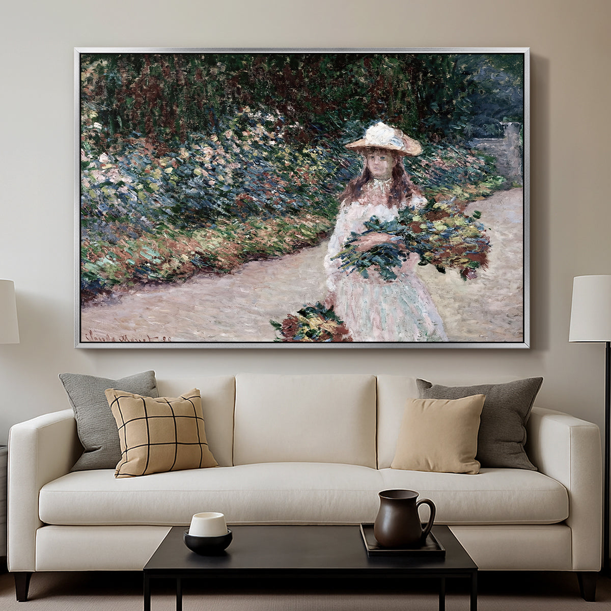 Young Girl in the Garden at Giverny, 1888 by Claude Monet displayed in a silver floater framed canvas above a sofa in a clean living room.