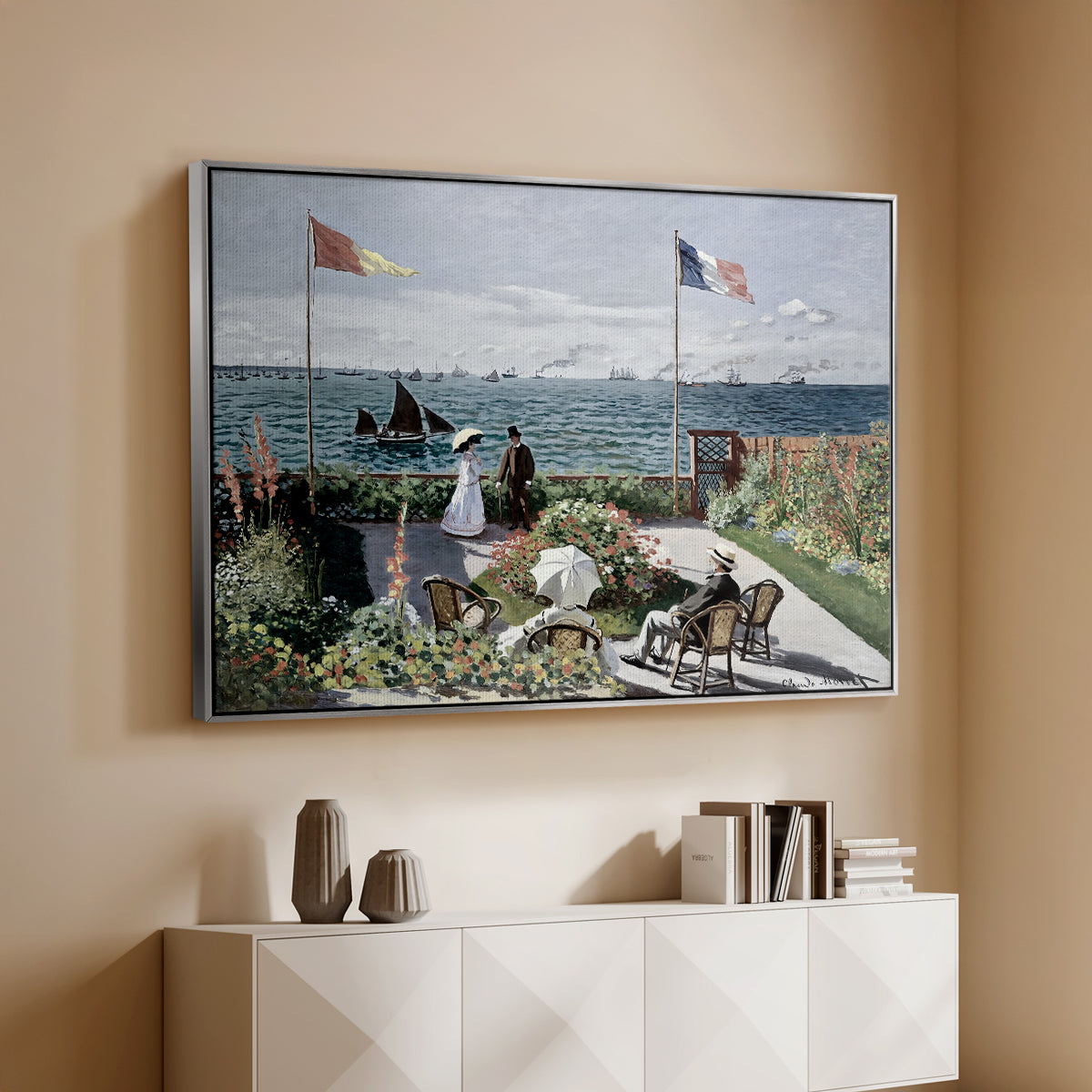 Silver floater framed canvas of Garden at Sainte-Adresse, 1867 by Claude Monet, featuring an impressionist coastal garden with people and ocean view above a console cabinet in a minimalist entryway.