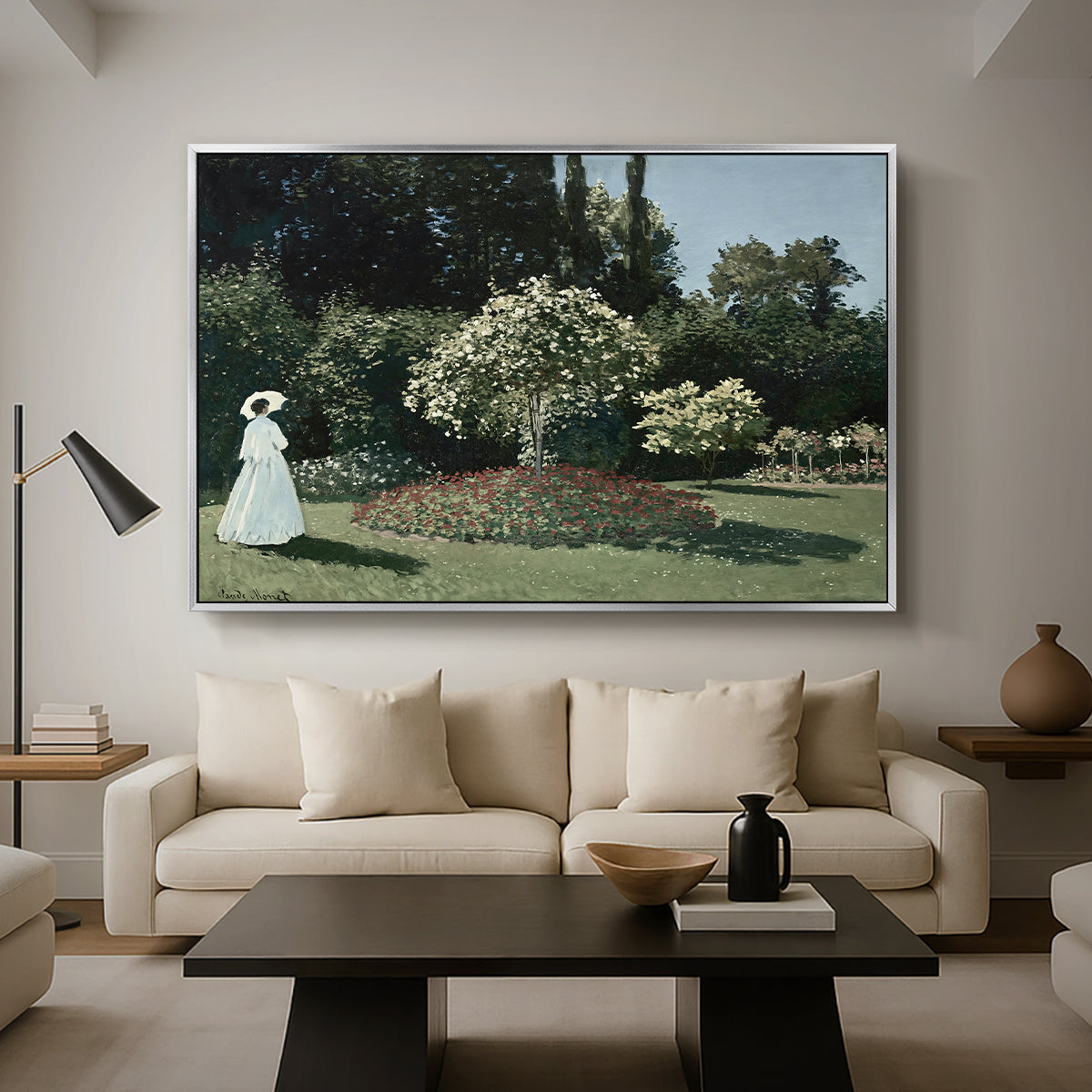 Woman in the Garden, Sainte-Adresse, 1867 by Claude Monet as a silver floater framed canvas featuring a woman standing in garden surrounded by flowers and greenery, displayed above a sofa in a modern living room.