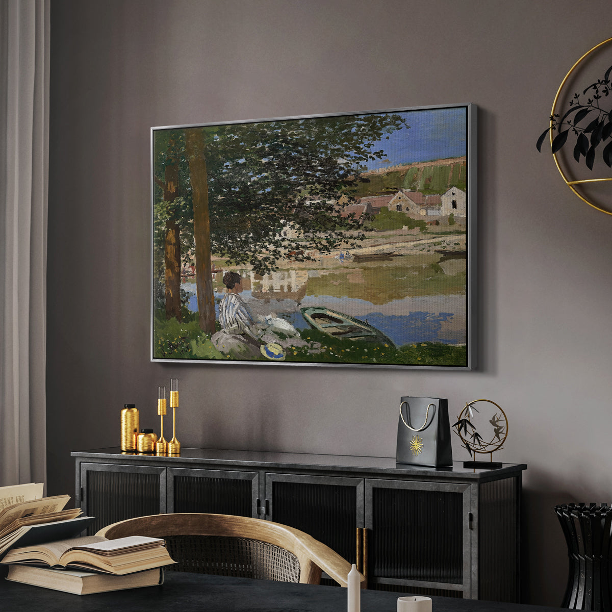 On the Bank of the Seine, Bennecourt, 1868 by Claude Monet in a silver floater framed canvas featuring an impressionist landscape with people relaxing along the Seine, displayed above a desk in a dark home office interior.