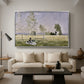 Summer (L'ete), 1874 by Claude Monet as a silver floater framed canvas featuring a woman seated in grassy field beneath tree in bright summer landscape, displayed above a sofa in a modern living room.