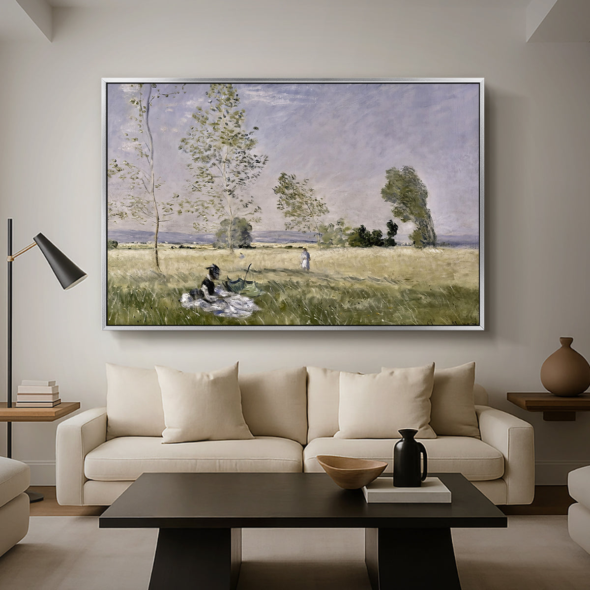 Summer (L'ete), 1874 by Claude Monet as a silver floater framed canvas featuring a woman seated in grassy field beneath tree in bright summer landscape, displayed above a sofa in a modern living room.