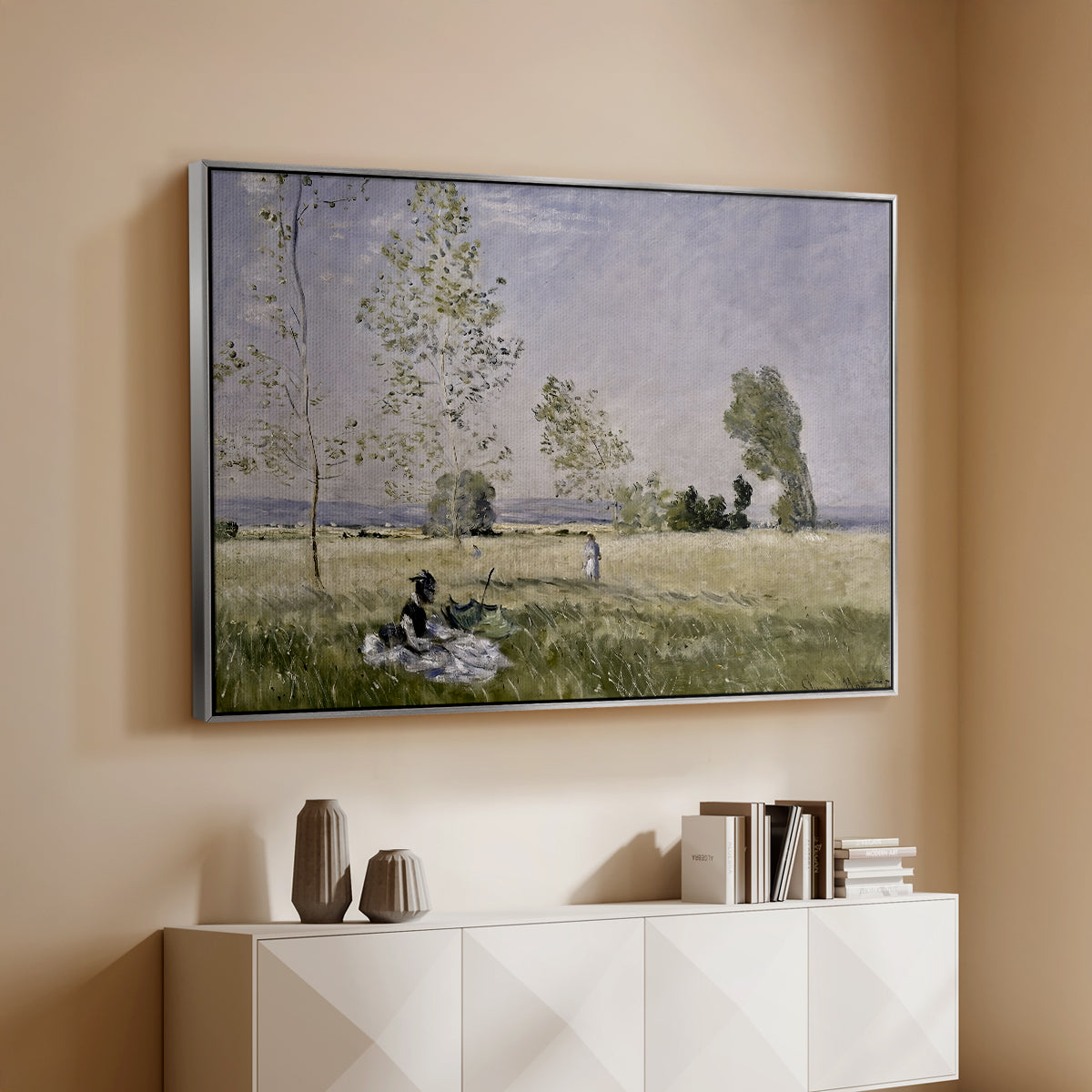 Silver floater framed canvas of Summer (L'ete), 1874 by Claude Monet, featuring an impressionist countryside scene with figure resting in shade above a console cabinet in a minimalist entryway.