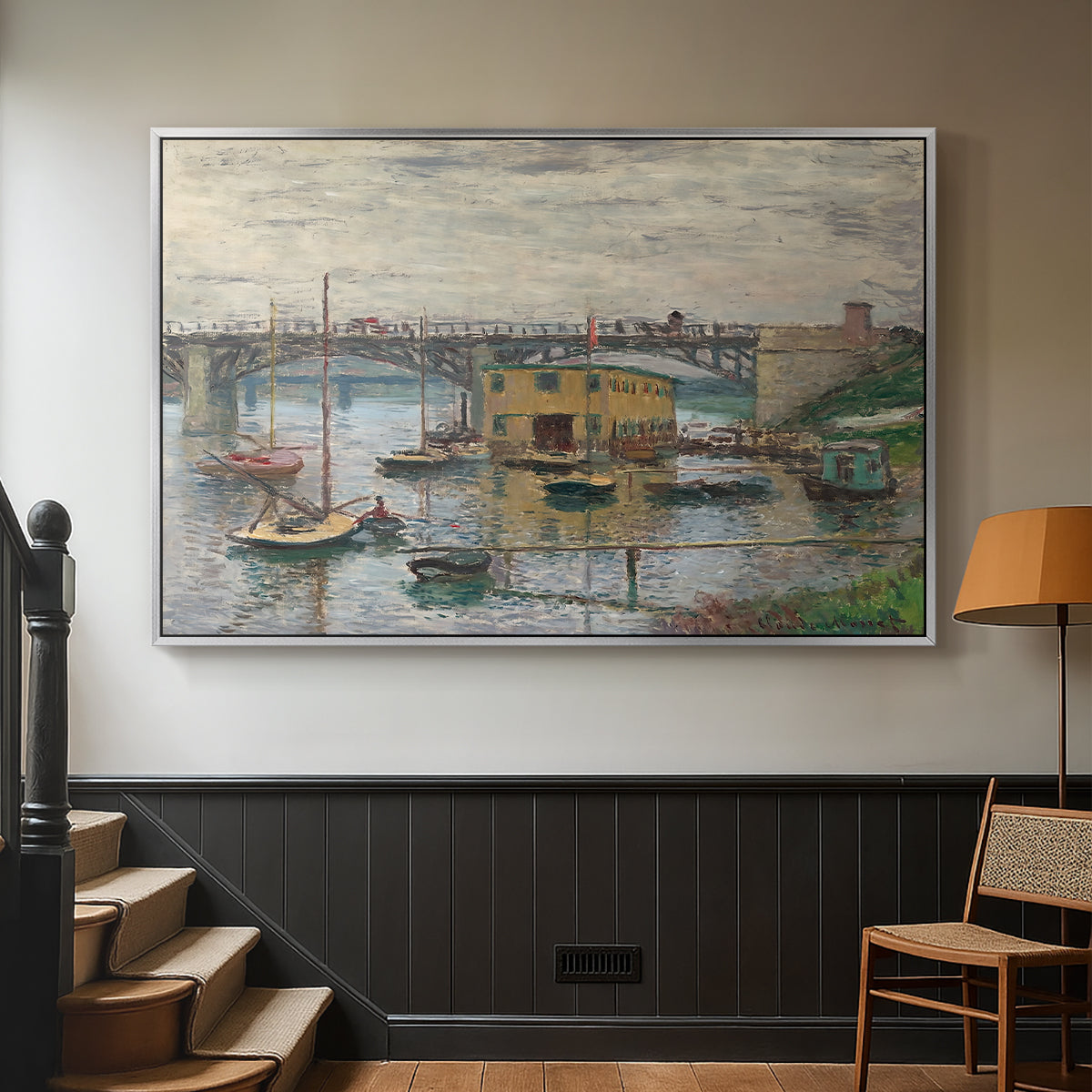 Silver floater framed canvas featuring a subdued urban landscape with structure spanning river, displayed in a hallway near a staircase.