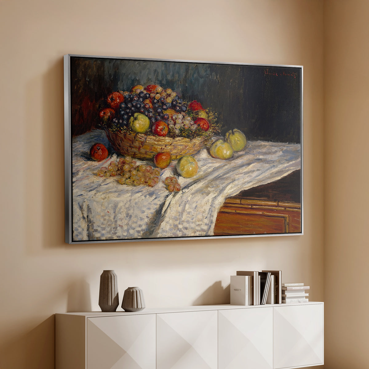 Silver floater framed canvas of Still Life with Apples and Grapes, 1880 by Claude Monet, featuring an impressionist still life of fruit placed on cloth-covered surface above a console cabinet in a minimalist entryway.
