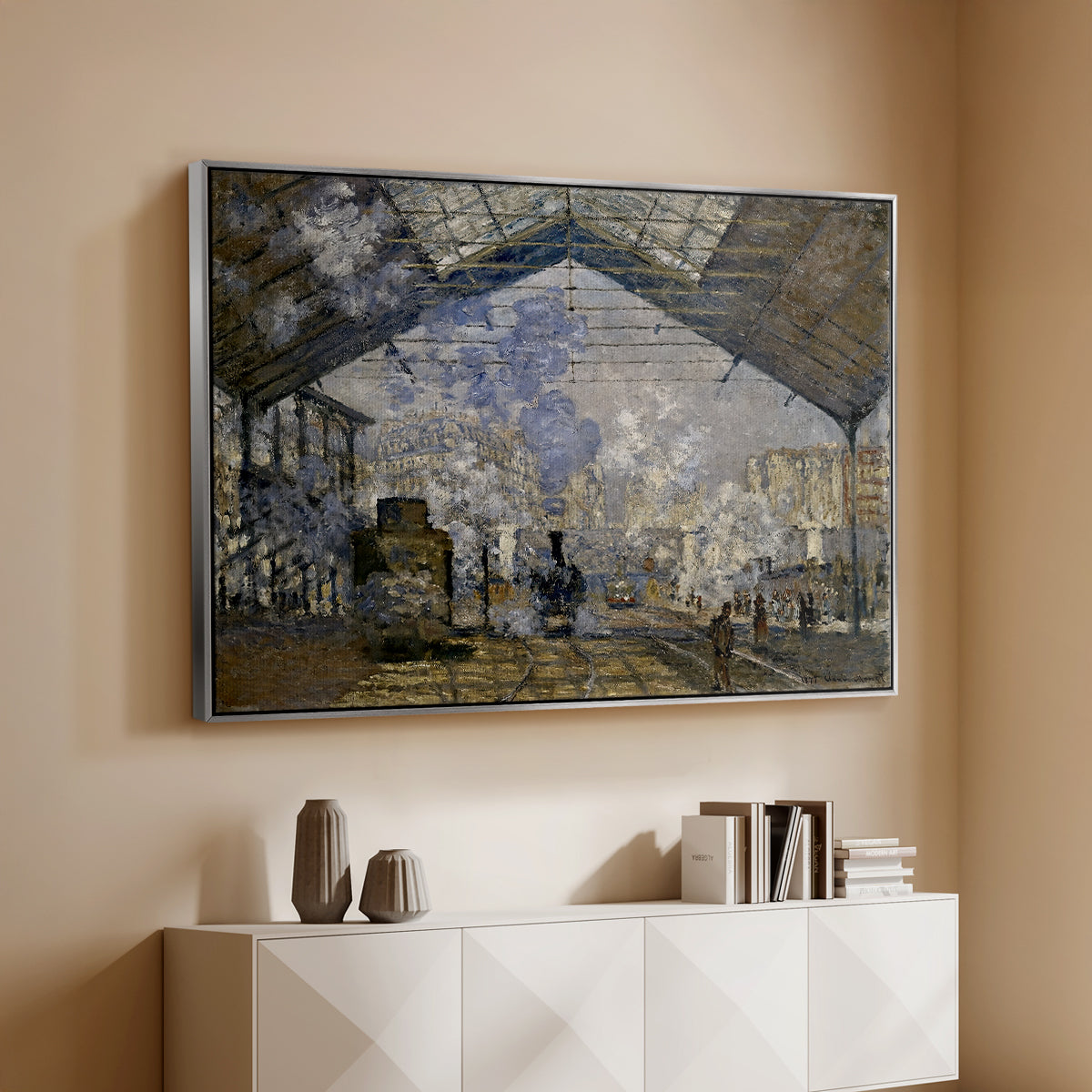 Silver floater framed canvas of The Gare Saint-Lazare, 1877 by Claude Monet, featuring an impressionist scene of trains and smoke inside busy railway station above a console cabinet in a minimalist entryway.