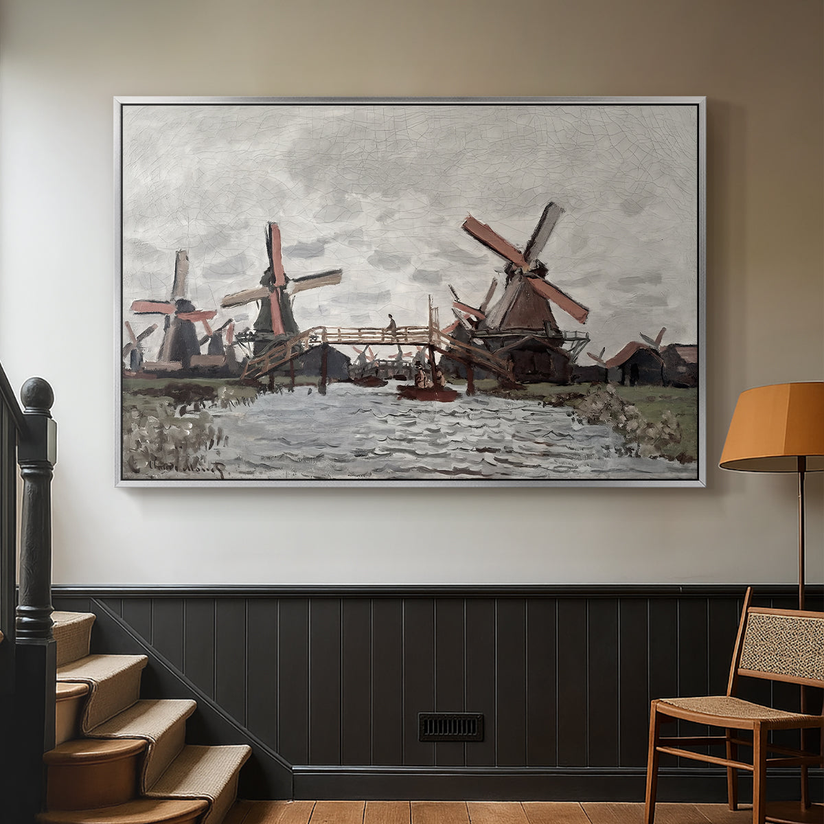 Silver floater framed canvas featuring a landscape featuring windmills and low horizon sky, displayed in a hallway near a staircase.