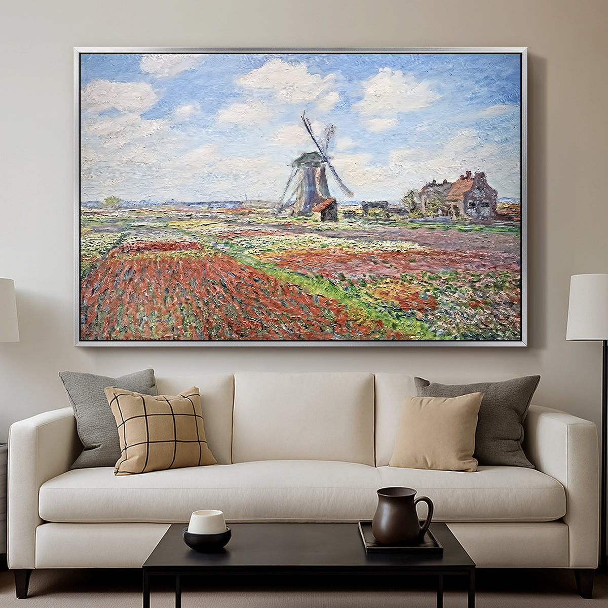 Tulip Fields with the Rijnsburg Windmill, 1886 by Claude Monet displayed in a silver floater framed canvas above a sofa in a clean living room.