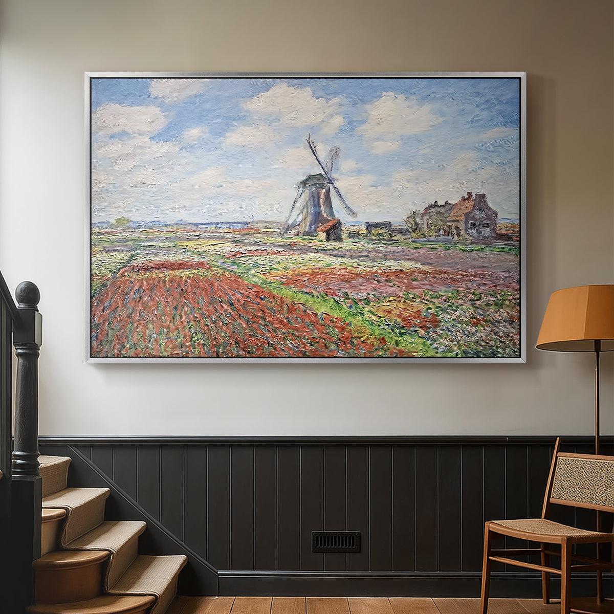 Silver floater framed canvas featuring a rural scene with patterned rows of flowers and windmill, displayed in a hallway near a staircase.