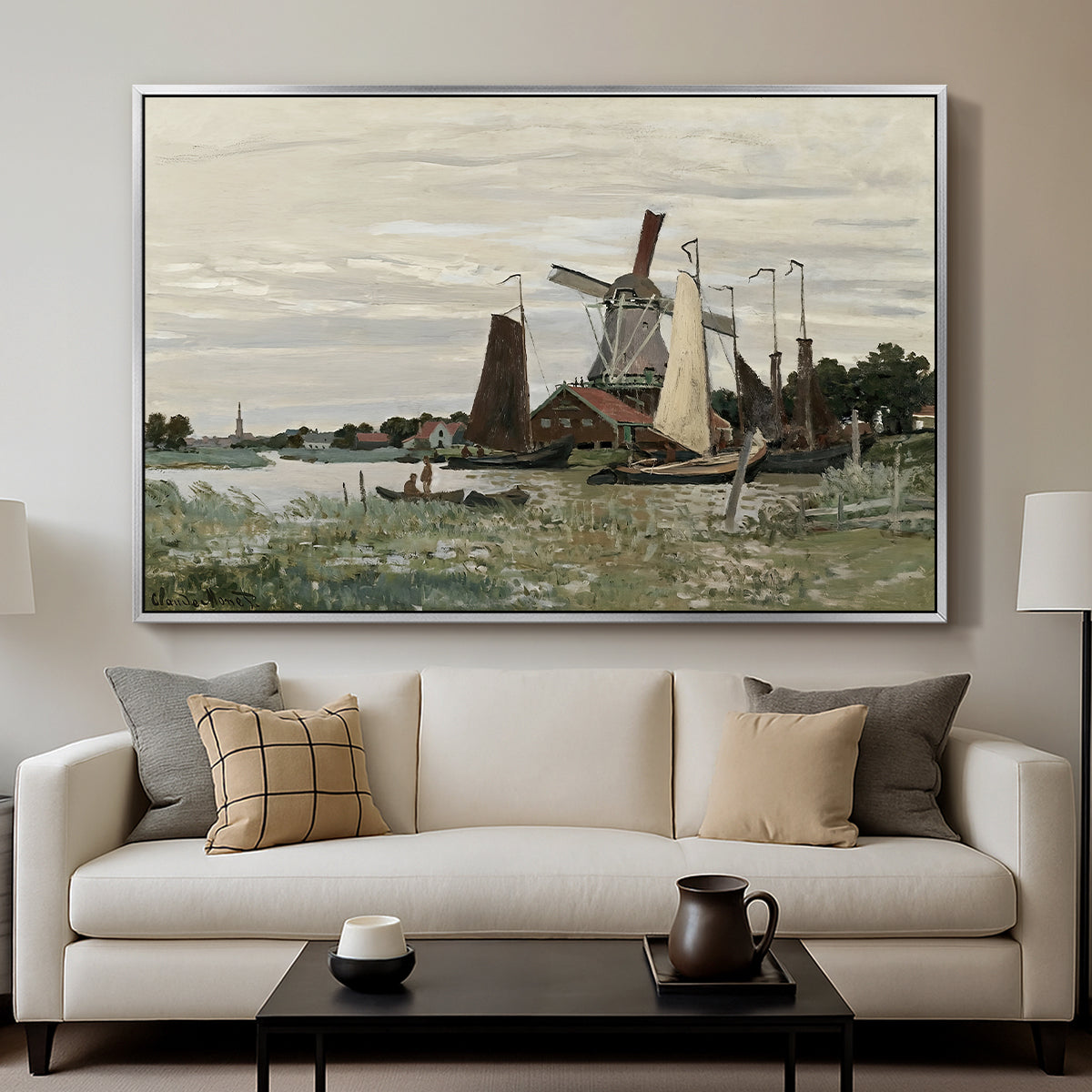 Windmill at Zaandam, 1871 by Claude Monet displayed in a silver floater framed canvas above a sofa in a clean living room.