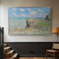 Silver floater framed canvas featuring an elevated shoreline path with figures and bright sky, displayed in a hallway near a staircase.