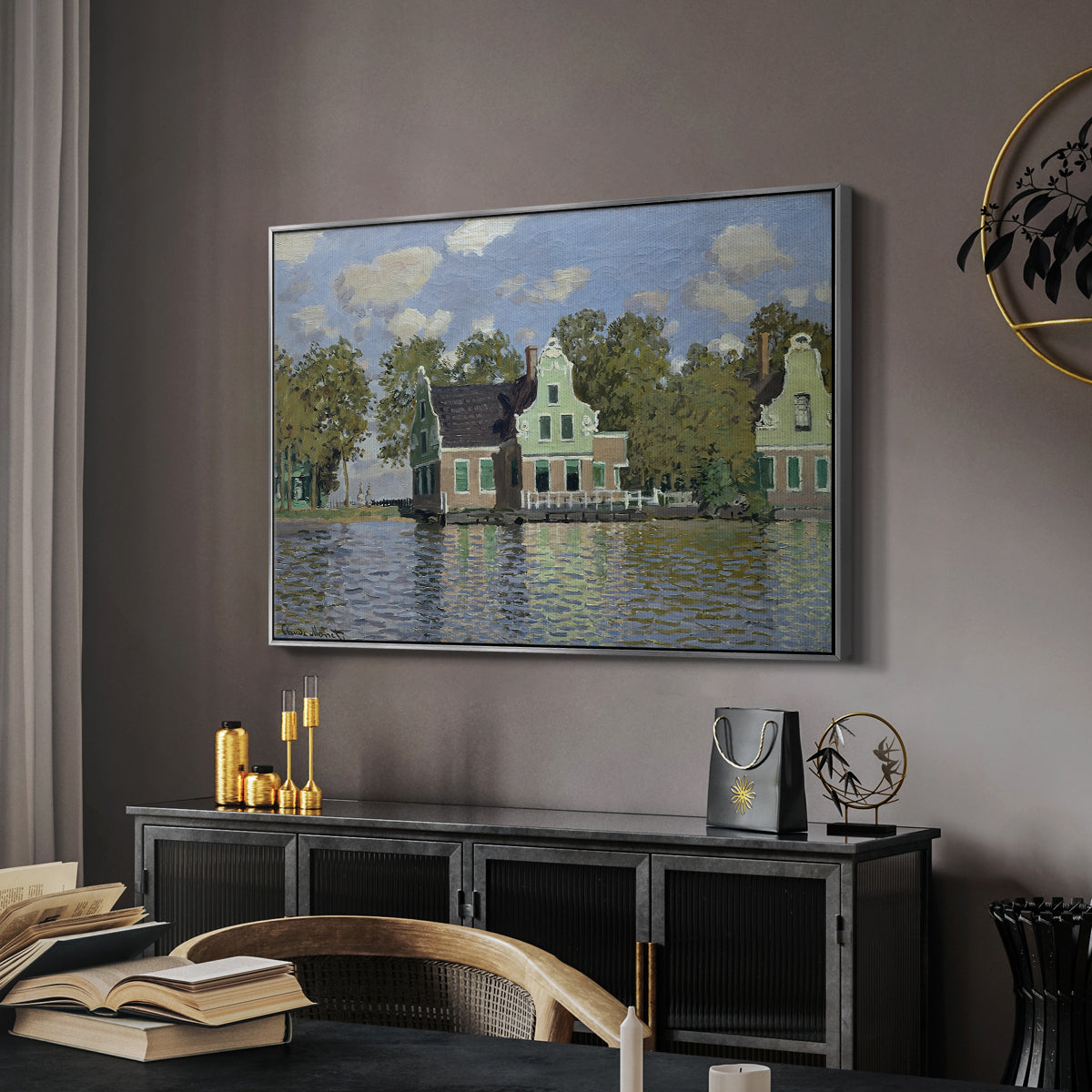 Houses on the Zaan River at Zaandam, 1871 by Claude Monet in a silver floater framed canvas featuring a peaceful canal scene with houses mirrored in water, displayed above a desk in a dark home office interior.