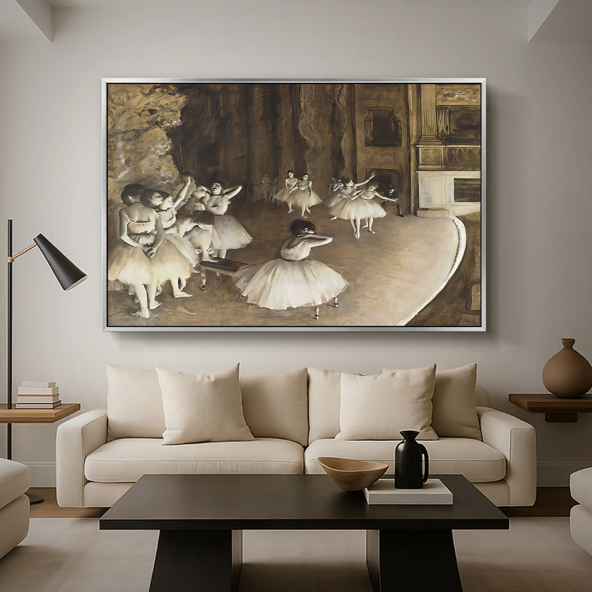 The Rehearsal of the Ballet Onstage, 1874 by Edgar Degas as a silver floater framed canvas featuring ballerinas rehearsing on stage with set backdrop and lighting, displayed above a sofa in a modern living room.