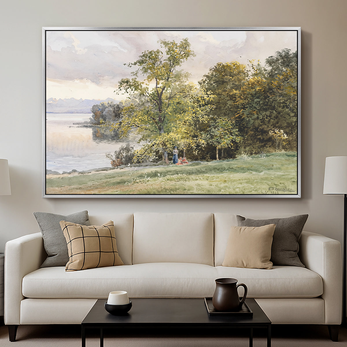 Landscape at Lake Starnberg, 1890 by Edward Theodore Compton displayed in a silver floater framed canvas above a sofa in a clean living room.