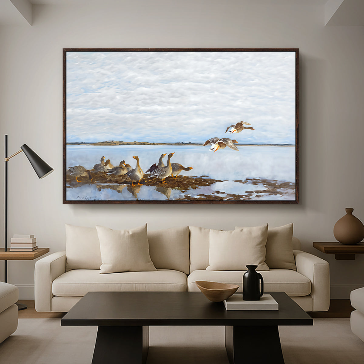 Greylag Geese (Grågäss), 1922 by Bruno Liljefors as a walnut floater framed canvas featuring a group of geese gathered near water in a natural wetland landscape, displayed above a sofa in a modern living room.