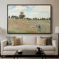 The Poppy Field near Argenteuil, 1873 by Claude Monet displayed in a walnut floater framed canvas above a sofa in a clean living room.