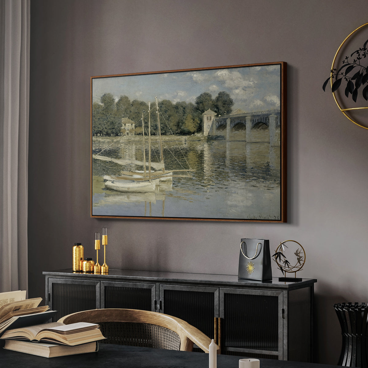 The Bridge at Argenteuil, 1874 by Claude Monet in a walnut floater framed canvas featuring a bright landscape featuring bridge and sailboats on calm water, displayed above a desk in a dark home office interior.