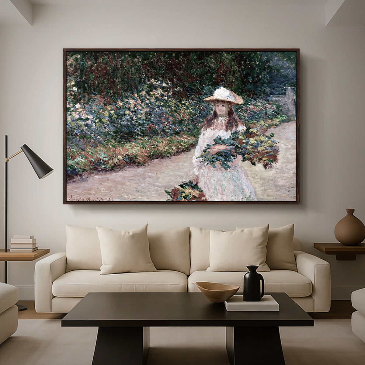 Young Girl in the Garden at Giverny, 1888 by Claude Monet as a walnut floater framed canvas featuring a young girl seated in lush garden surrounded by blooming flowers, displayed above a sofa in a modern living room.