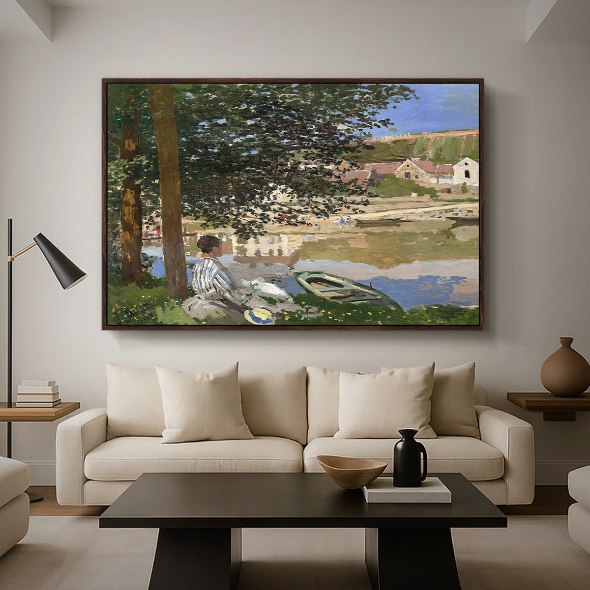 On the Bank of the Seine, Bennecourt, 1868 by Claude Monet as a walnut floater framed canvas featuring a woman and child seated along riverbank beneath trees in soft daylight, displayed above a sofa in a modern living room.