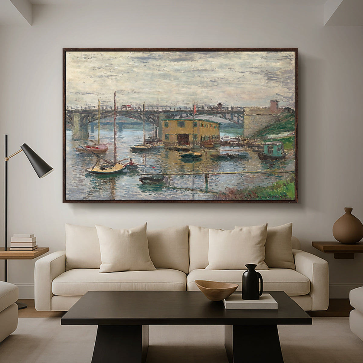 Bridge at Argenteuil on a Gray Day, c. 1876 by Claude Monet as a walnut floater framed canvas featuring a bridge crossing river under gray sky with muted reflections, displayed above a sofa in a modern living room.