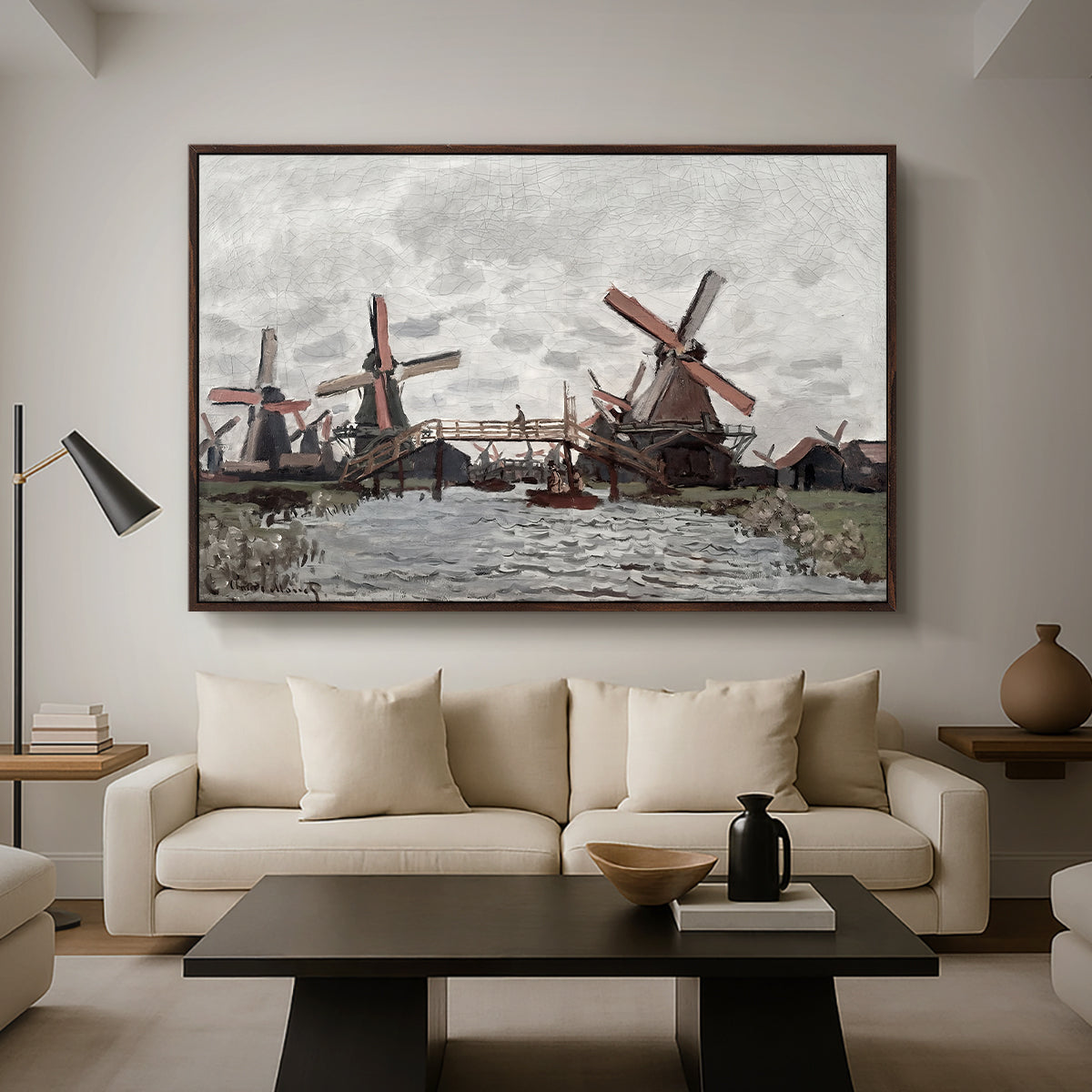Windmills near Zaandam, 1871 by Claude Monet as a walnut floater framed canvas featuring windmills standing beside water under open sky in rural landscape, displayed above a sofa in a modern living room.