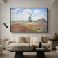 Tulip Fields with the Rijnsburg Windmill, 1886 by Claude Monet as a walnut floater framed canvas featuring colorful rows of tulip fields leading toward distant windmill, displayed above a sofa in a modern living room.