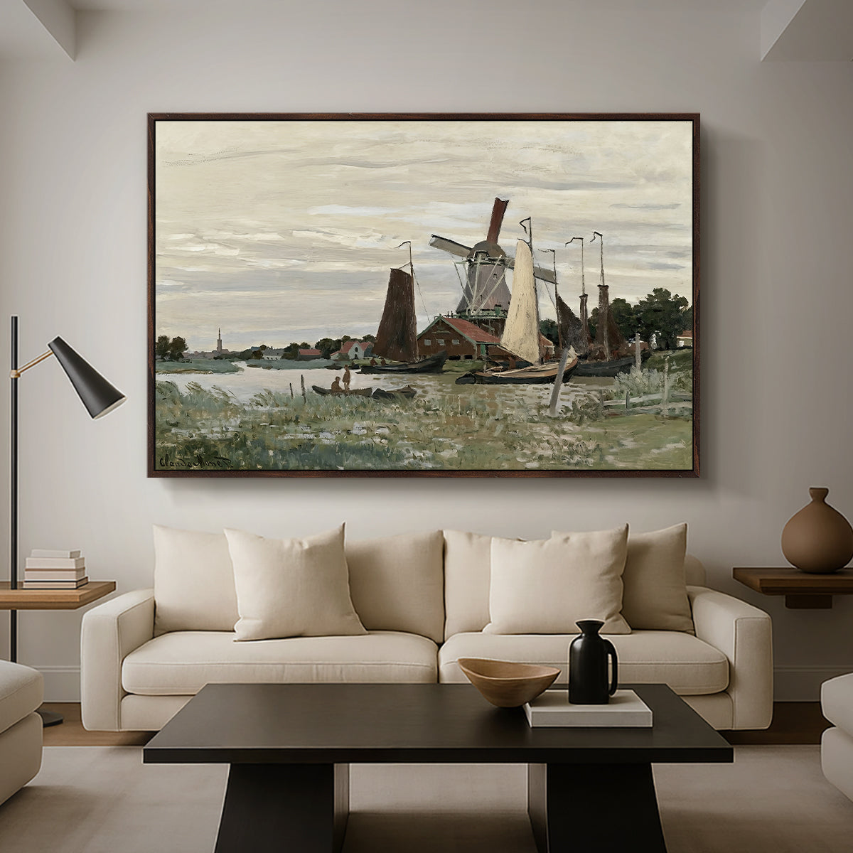Windmill at Zaandam, 1871 by Claude Monet as a walnut floater framed canvas featuring a single windmill beside water with surrounding buildings and sky, displayed above a sofa in a modern living room.