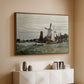 Walnut floater framed canvas of Windmill at Zaandam, 1871 by Claude Monet, featuring an impressionist depiction of windmill near riverbank above a console cabinet in a minimalist entryway.