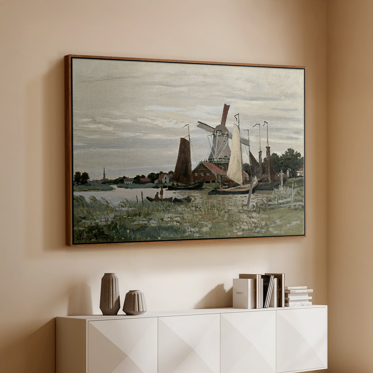 Walnut floater framed canvas of Windmill at Zaandam, 1871 by Claude Monet, featuring an impressionist depiction of windmill near riverbank above a console cabinet in a minimalist entryway.