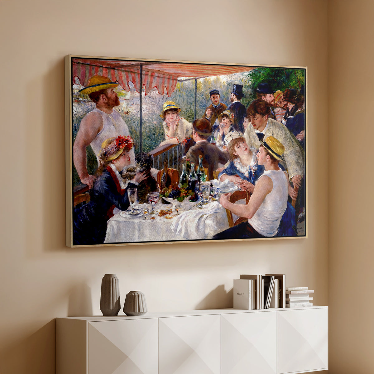Natural wood floater framed canvas of Luncheon of the Boating Party (Le Déjeuner des canotiers), 1880-1881 by Pierre-Auguste Renoir, featuring a lively gathering of men and women eating and socializing at outdoor table above a console cabinet in a minimalist entryway.