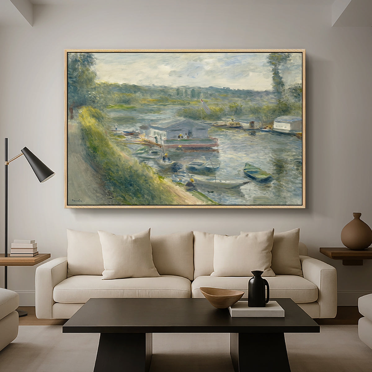 Wash-House Boat at Bas-Meudon, c. 1874 by Pierre-Auguste Renoir as a natural wood floater framed canvas featuring a floating wash-house boat along a riverbank with figures working nearby, displayed above a sofa in a modern living room.