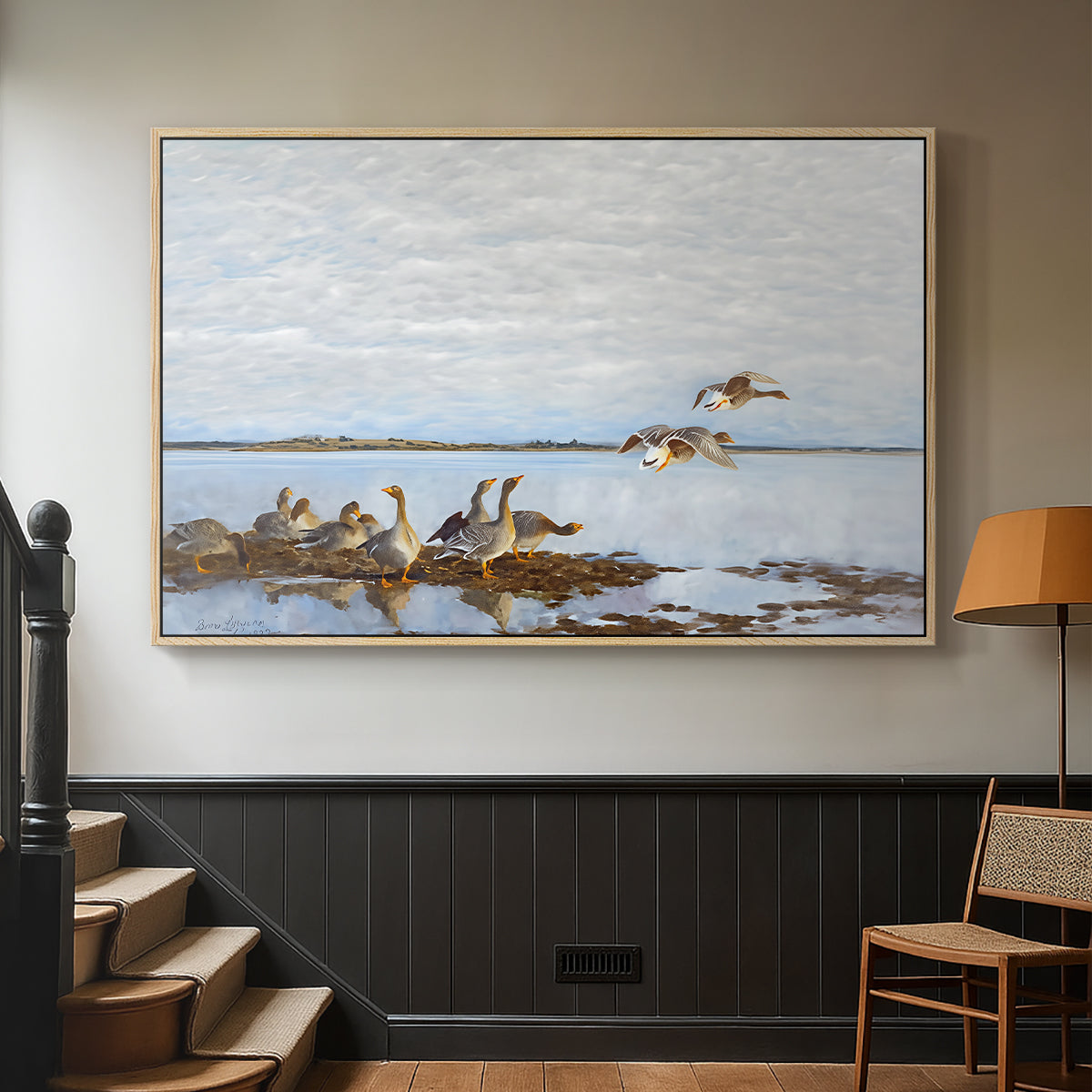 Natural wood floater framed canvas featuring a flock of geese positioned along marshy terrain, displayed in a hallway near a staircase.