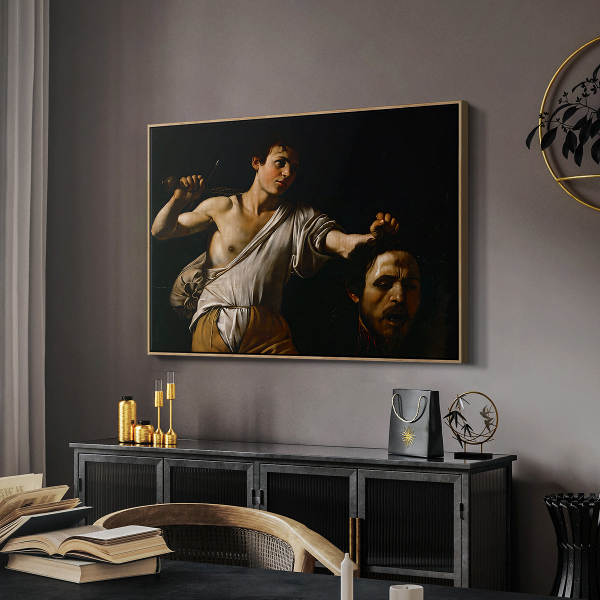 David with the Head of Goliath (Vienna Version), c. 1607 by Caravaggio in a natural wood floater framed canvas featuring a Baroque depiction of youth holding severed head in shadowy setting, displayed above a desk in a dark home office interior.